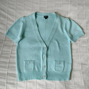 Kortärmad stickad kofta/tröja - storlek M - Kortärmad stickad kofta/tröja från Lindex. Bara använd en gång och i fint skick..55% akryl och 45% bomull. Storlek M.