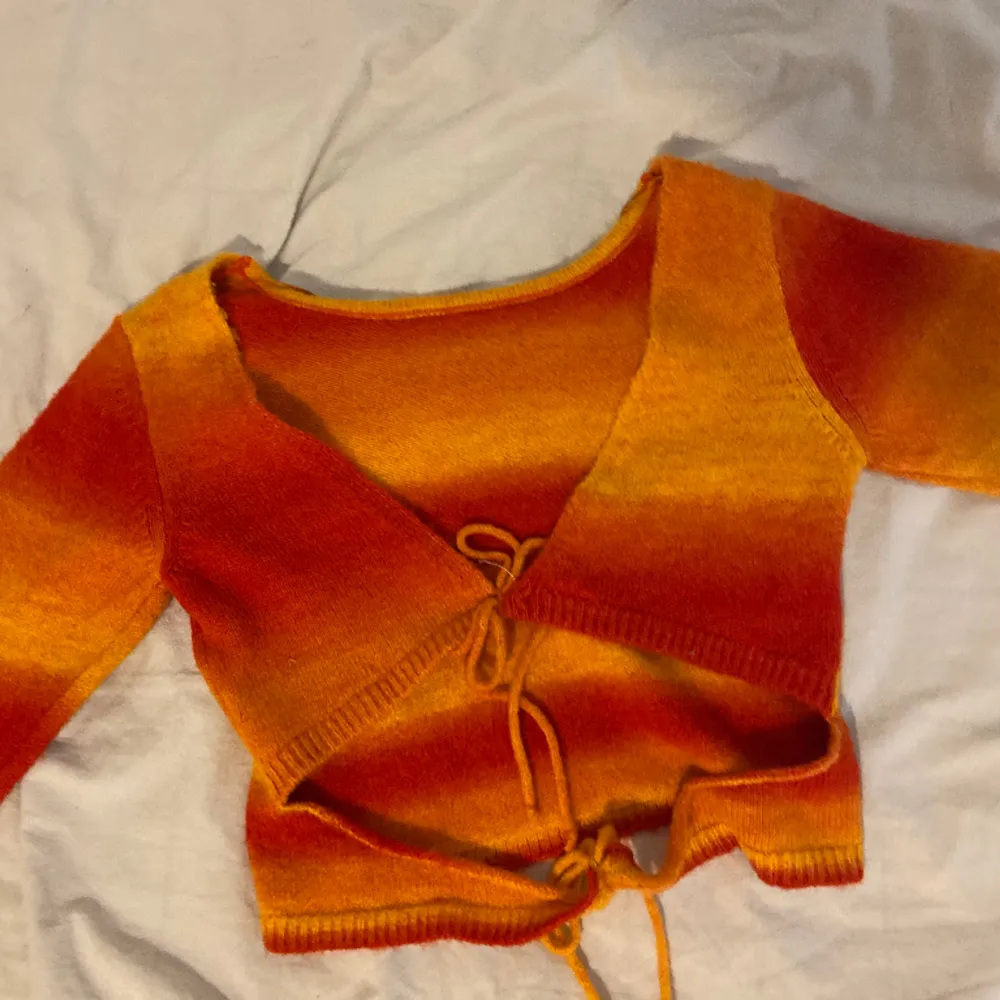 Orange/röd tröja med knytning från urban outfitters. Man kan ha den på båda hållen. Stickad, bra kvalité. Endast använd 1 gång.. Tröjor & Koftor.
