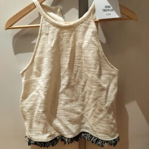 Fint set (topp+kjol) från Zara, storlek S lappar kvar - Garderobsrens! Sorry för skrynkliga plagg. Fint äggskalsvitt set i tyg med struktur från Zara, med fransar nedtill på både topp och kjol. Storlek S, lappar kvar och helt oanvända.