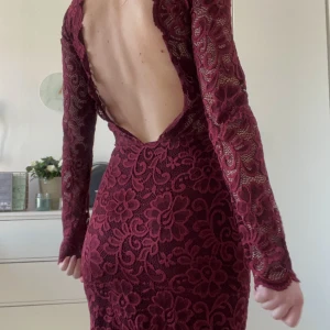 Klänning med öppen rygg - Klänning i vinröd spets med öppen rygg. Anspänt ett fåtal gånger och i fint skick.