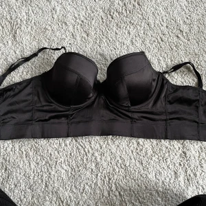 Bh / topp - Aldrig använd bh från H&M i satin liknande material. Funkar som festlig topp såväl som vanlig bh. Säljer pga aldrig kom till användning plus fel storlek. Storlek 75D. Tveka inte att höra av dig om du har frågor