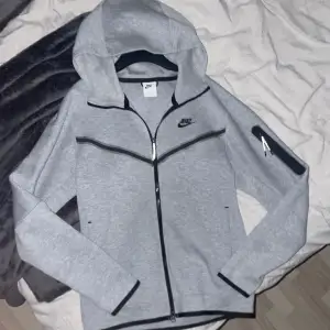 Grå Nike tech fleece hoodie. Den är i mycket bra skick, har endast använt den ett fåtal gånger. Storlek S