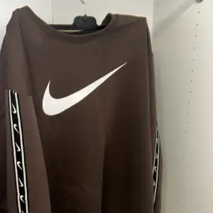 En brun nike tröja med striped armar som säljs pga inte används och i bra skick