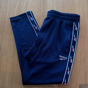 Reebok byxor  - Oanvända mörkblå byxor från Reebok. Finns även i svart, se annons i min profil.   Rensar ur min garderob från en hel del oanvända kläder🌼 Om du ser något mer i min profil som du gillar så skickar jag med det till dig också!😊 Fler kläder kommer!