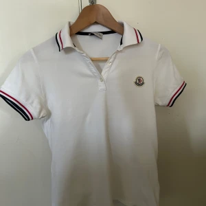 Moncler piké - Denna vita moncler pikén är i helt utmärkt skick nästan som ny. Den är i barnstorlek 12 år.