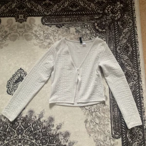 Tunn kofta - Säljer en tunn vit kofta, storlek XS/S. Tvättad och i utmärkt skick. Köpt från H&M för 200 kr, säljs nu för 100 kr eller enligt överenskommelse. Perfekt för att lägga till en touch av elegans till din outfit! ❤️