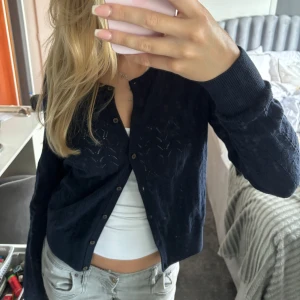 Svart kofta - En marinblå kofta med fint mönster  knappar framtill. Koftan har långa ärmar och ribbstickade muddar vid ärmslut och nederkant.