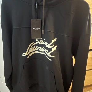 Saint Laurent - Säljer denna sjukt snygga hoodie från Saint Laurent. Skicken är 10/10 och storleken är L men passar dock som ett M. Hör av dig om du är intresserad för och köpa eller byta!!