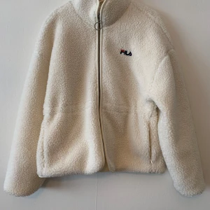 FILA jacka - Vit teddy jacka från FILA, använd fåtal gånger, bra skick, nästan nyskick, inget slitage. Storlek L.  Kan mötas upp i Stockholm och Uppsala. 