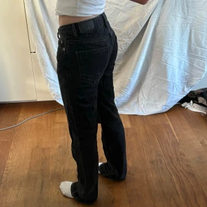 Svarta jeansbyxor - Ett par svarta jeansbyxor i storlek xxs. Byxorna har en låg midja och en rak passform. De är tillverkade i ett slitstarkt denimtyg och har klassiska fem fickor samt knapp- och dragkedjestängning.