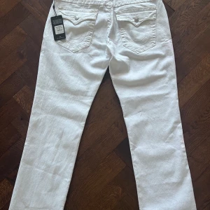 🙅‍♂️OANVÄNDA🙅‍♂️🤠TRUE RELIGION🤠‼️ RICKY‼️ - Ett par vita true religion jeans som är köpta i USA 🇺🇸 Tampa! Då jag föll för dem när jag var på semester där! Men plånboken skriker och jag måste dra in lite kapital till sommarplanerna, så dessa fina jeans måste tyvärr hitta ett nytt hem🤧. Fråga på!