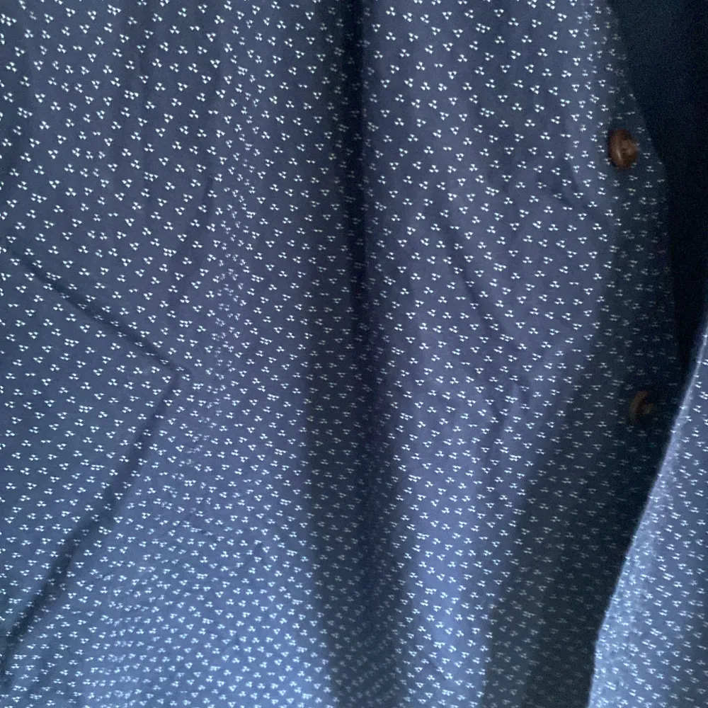 Nyskick. Marinblå skjorta med diskret mönster. Detaljfoto taget så mönstret syns. Skjortor.
