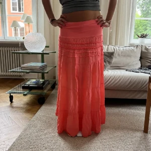 Lång kjol  - Skit snygg kjol i corallfärg, ingen lapp så vet inte vart den är ifrån eller storlek men kan skicka mått om det behövs men den passar Xs-L 