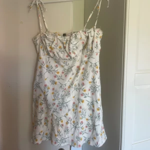Klänning med blommor - Vit klänning med blommor på! Perfekt till sommaren.  Bra skick.