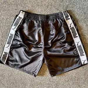 Svarta glansiga Puma shorts stl XL i bra skick,enstaka tråddrag kan förekomma men i bra skick!
