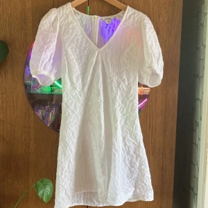Klänning Monki - Hej! Säljer en knappt använd klänning från Monki. Tunt vitt tyg med fina detaljer gör att man kan ha den både till stranden och på festliga tillfällen. Kanske till studentfest eller skolavslutning?Dragkedja bak och lite puff i ärmarna. Skicka dm vid frågor.