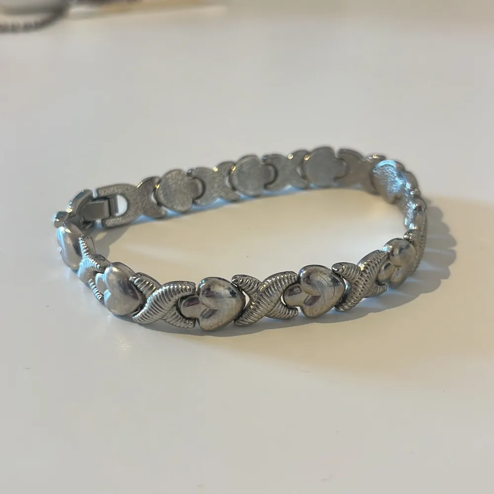 Ett vackert silverfärgat armband med ett mönster av sammanlänkade hjärtan och kryss. Armbandet har en säkerhetslåsning och en elegant design som passar för olika tillfällen. Köptes i Turkiet men aldrig använt då det är för stort. Finns lite små repor här o där då de legat i en låda. . Accessoarer.