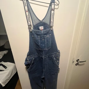 Tommy Jeans denim hängselbyxor  - Storlek L, ( men beror kanske mer på hur man vill att den sitter) köpt från Zalando, använd Max 1 gång, säljer då jag tror den kommer att komma till mer användning hos någon annan.