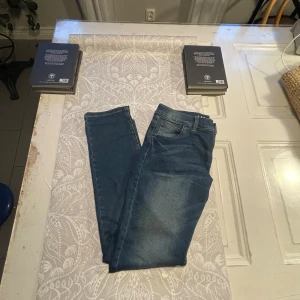 Blå jeansbyxor - Ett par oöppnade blå jeansbyxor i storlek 170. Byxorna har en klassisk design med fem fickor och en dragkedja.