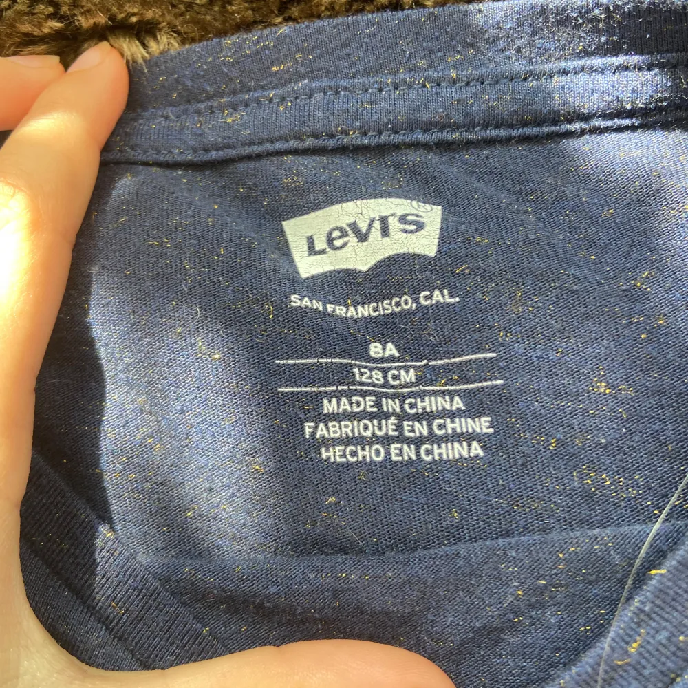 En mörkblå Levi’s t-shirt med guldstänk i storlek 128.. T-shirts.