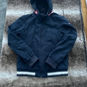 Tommy Hilfiger jacka - Snygg Tommy hilfiger vårjacka! Sällan använd då den inte riktigt är min stil, så bara legat i garderoben. Inga skador på jackan och den är i 10/10 skick! Så om du vill ha en jacka i nyskick för billigt pris köp då denna! Storlek 176 men passar XS!