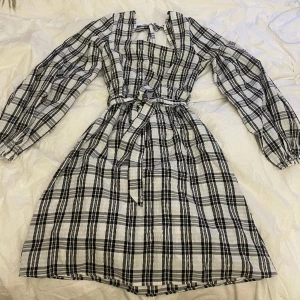 Klänning med puffärmar - Svart vit rutig klänning med puffärmar och knytning både runt midja och vid rygg