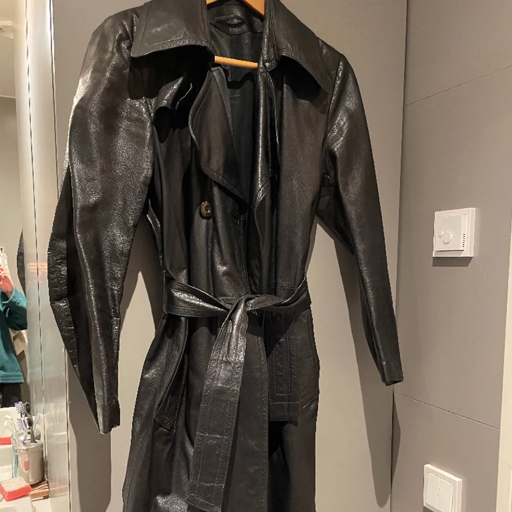 Vintage svart läderkappa/trenchcoat i storlek S/M, äkta läder. OBS hål i vänster ficka, därav priset 🙏🏻. Jackor.