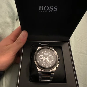 Hugo boss klocka - Butikspris: 4995kr Armbandsfärg- silver Armbandsmaterial- rostfritt stål Artikelnummer- 1513359 Boettfärg- svart Boettmaterial- rostfritt stål Funktion- datum Funktion- Kronograf  Funktion- stoppur  Klocktyp- analog Urtavla färg- grå med silverdetalj