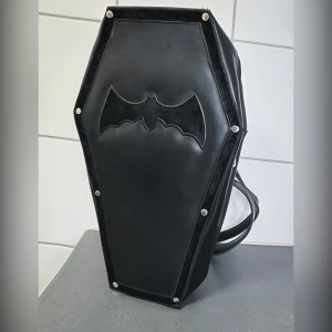 Alchemy coffin ryggsäck/väska - Alchemy coffin väska/ ryggsäck Går att använda både som axelremsväska och som ryggsäck  Mått ca 34 x 21 x 10 cm Endast använd fåtal gånger ute. Den är i fint skick vad jag kan se
