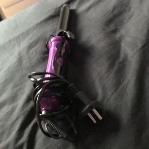 Lila locktång från Severin - Säljer en lila locktång från Severin Hair Care. Den har en svart och lila design med en röd indikatorlampa och en temperaturinställning på 210 grader. Perfekt för att skapa snygga lockar till fest eller vardag. Använd några gånger men fungerar utmärkt!