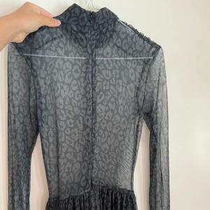 Mönstrad långklänning i mesh - Säljer en superfin långklänning i mesh med leopardmönster. Klänningen är mörkgrå och har långa ärmar. Den är genomskinlig och har en dragkedja i ryggen. Perfekt för fest eller en utekväll! 🖤