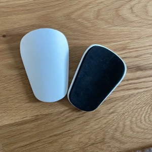 Vit benskydd - Säljer ett par vita mini benskydd i nyskick. De är lätta och bekväma att ha på sig under matchen. Perfekta för att skydda dina ben från stötar och slag. Passar bra för både träning och match.