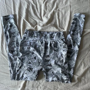 Mönstrade leggings från Funk - Säljer ett par snygga mönstrade leggings från Funk i storlek M. De är vita och grå med ett coolt geometriskt mönster. Perfekta för träning eller en avslappnad dag. Materialet är elastiskt och bekvämt, vilket gör dem idealiska för alla typer av aktiviteter. Passa på att köpa dessa unika leggings!