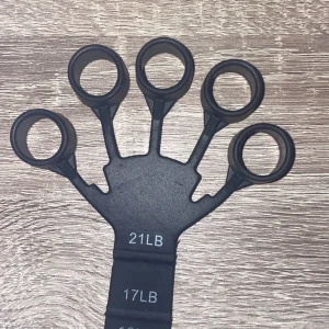 Svart fingertränare - Säljer en svart fingertränare med olika motståndsnivåer. Perfekt för att stärka fingrarna och förbättra greppstyrkan. Den har fem ringar för fingrarna och är märkt med motståndsnivåer på 21LB och 17LB.