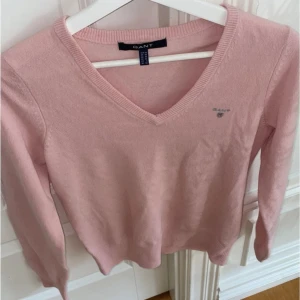 Rosa tröja från GANT - En mjuk och bekväm rosa tröja från GANT med v-ringning. Tröjan har långa ärmar och en liten GANT-logga på bröstet., kom privat för mer frågor eller bilder 🫶🏻
