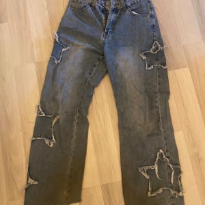 Grå jeans med stjärndetaljer från Romwe - Säljer ett par grå jeans från Romwe i storlek S (EUR 36). De har coola stjärndetaljer med slitningar på benen och en avslappnad passform. Perfekta för en grunge/ skater look! 