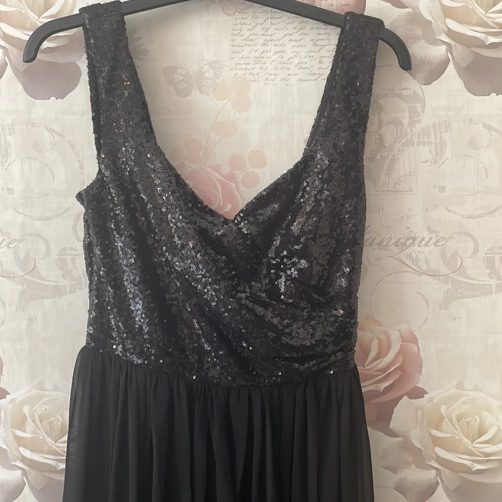 Säljer en superfin svart långklänning med paljetter upptill. Klänningen har en djup v-ringning och är ärmlös, vilket gör den perfekt för fest eller bal. Kjoldelen är flödande och ger en elegant look. Den är i nyskick och redo att bäras till nästa stora event! Använd en gång, säljer då den inte kommer till användning mer. Köparen står för frakten!. Mekot.