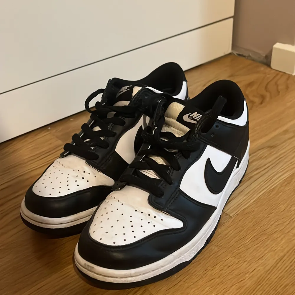 Säljer ett par snygga svartvita Nike Dunk sneakers. De är i bra skick dock lite cresade, har en klassisk design med svart och vitt läder. Perfekta för både vardag och fest! Skorna har snörning och en bekväm passform.. Skor.