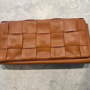 Clutch i konstläder - Superfint skick så inga märken på den. Höjd: 13 cm  Bredd: 27,5 cm Djup: 5 cm Clutchen stängs med ett magnetlås 