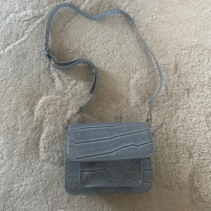 Liten ljusblå väska från Hvisk. Stängs med magnetknäppe och har en ficka på insidan💕 - Bra skick 