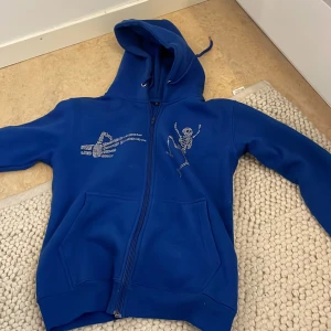 Zip-up med rhinestones - Blå zip-up hoodie med rhinestones på bröstet och ärmarna storlek S män