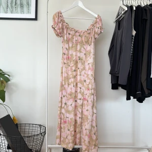 Blommig långklänning från H&M  - En supersöt blommig långklänning med slit. I storlek 42 från H&M. Använd enstaka gånger, så i fint skick! Den stängs igen av en dragkedja. Toppen är stretchig, men däremot är inte själva kjolen stretchig. 