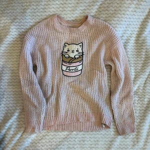 Rosa stickad tröja - Rosa stickad tröja med gulligt mönster av katt. Fick av kompis, tror att den är från New Yorker från början. Använd typ 2 ggr, superfint skick.