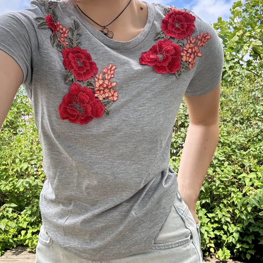 Grå t-shirt med påsydda, broderade blommor samt blad från TopShop. Bara använd 2-3 gånger! Storlek: 36. Material: 50% bomull + 50% modal. :). Toppar.