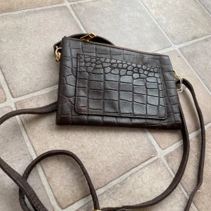 Annica Vallin väska - Ny läderväska från Annika Vallin. Snygg mörkbrun färg. Måtten på väskan: Bredd 20 cm, höjd 15 cm och djup 13 cm.