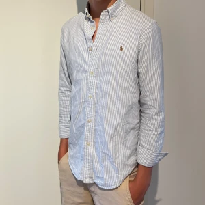 Ralph lauren skjorta  - Hej nu säljer vi en randig Ralph lauren skjorta med ljusblåa och vita ränder.  Modellen är ca 175cm och den passar men den börjar bli lite kort i armarna så vi skulle säga att om du är mellan 170-175 sitter den perfekt. 