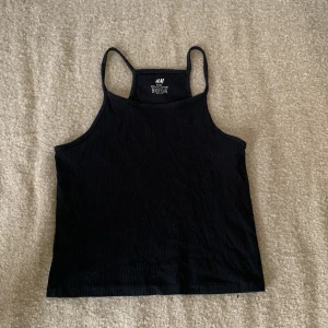 Svart linne från H&M - Ett svart linne från H&M tillverkat av ekologisk bomull. Linnet har smala axelband och är ribbad.