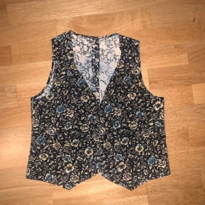 Blommig väst🍂 - Jättefin blommig väst med lite 70-tals-känsla! Står ingen storlek i men gissar M-L🪴köpte på nätet men den passade tyvärr inte som jag hade tänkt:( skriv för fler bilder eller frågor🍂