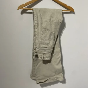 högmidjade jeans - ett par ljus beige:a jeans som är väldigt högmidjade. jeansen är tajta vid midjade o sedan sitter löst nedåt. dessa jeans är använd ganska många gånger men de är fortfarande i bra skick. 