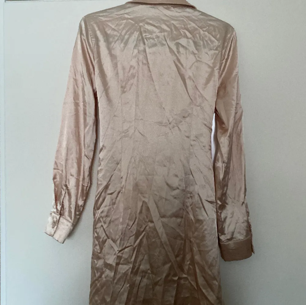 En skjortklänning med knytning som går att knyta både fram och bak. Halkigt material från Cider. Klänningar.